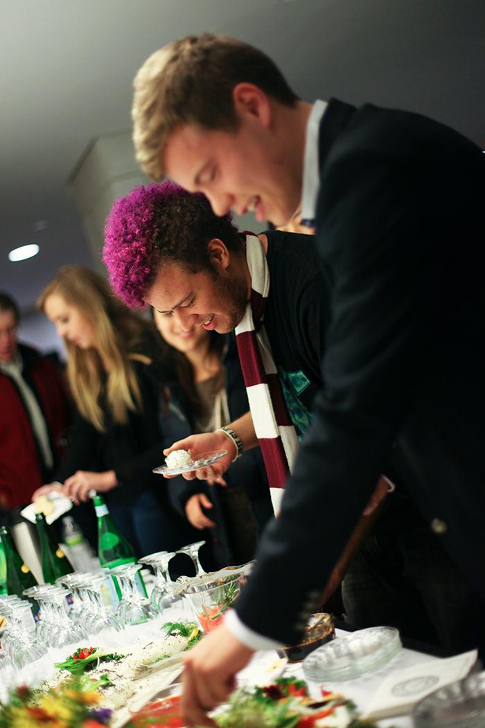 A group of students picking up refreshments off of a reception table